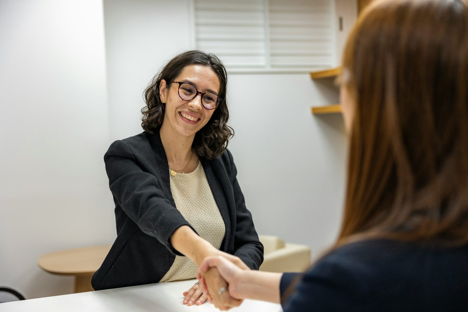 Une femme serrant la main d'une femme assise à une table.